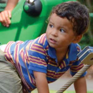 All ages of children climbing and swinging on modern playground equipment