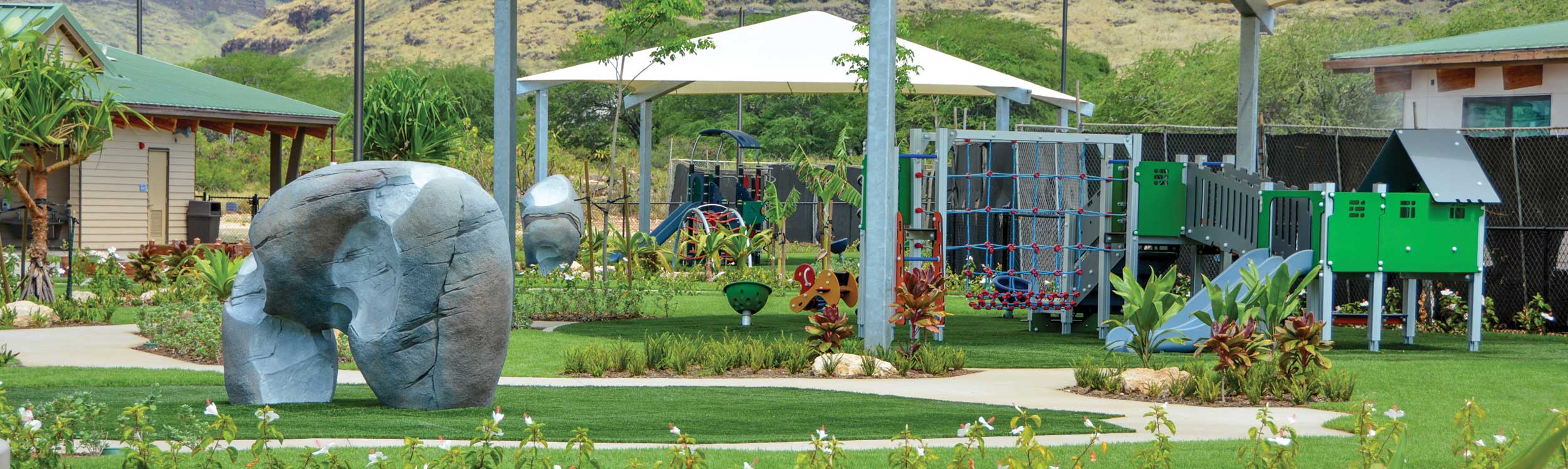 Shade structure over play equipment with rock climbing toy